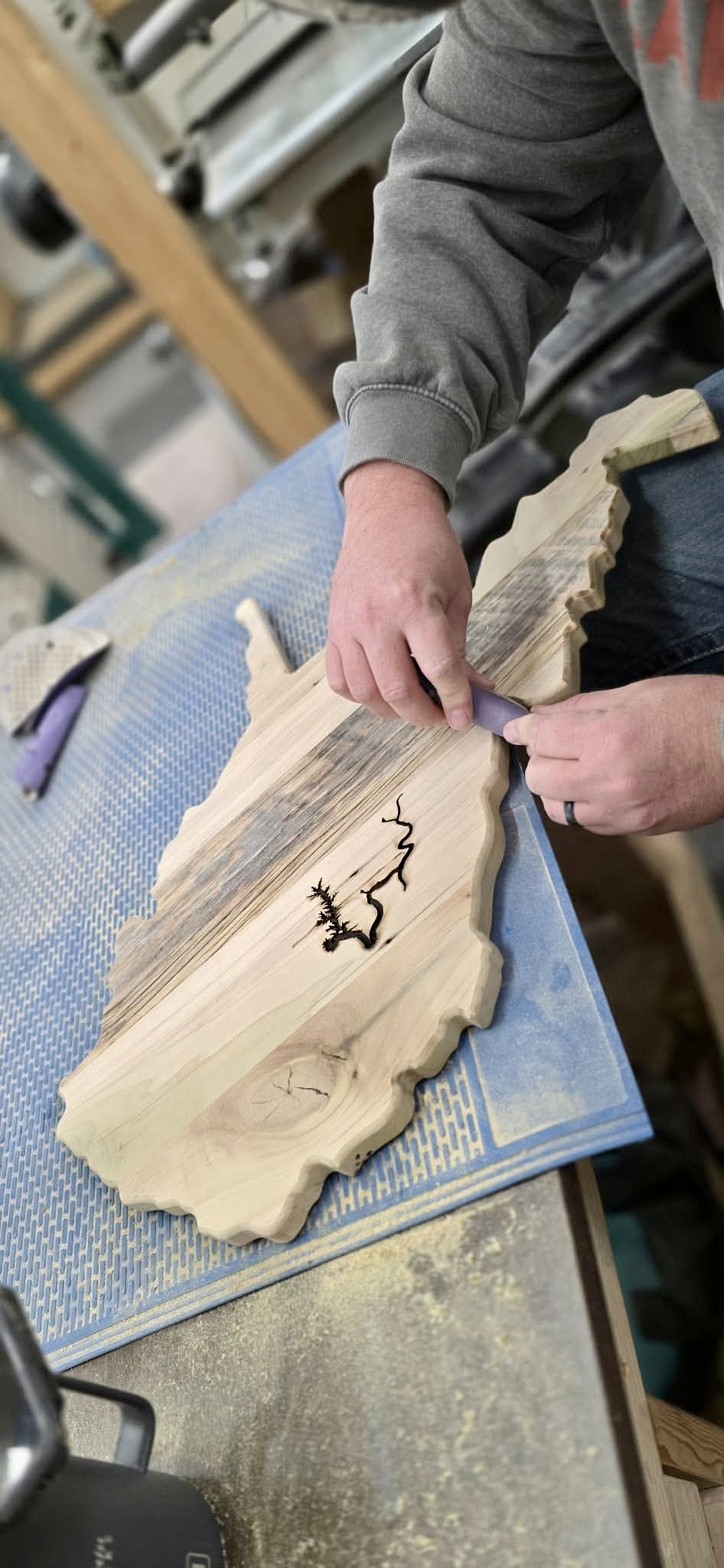A handcrafted live-edge West Virginia wood piece being detailed by hand in the workshop